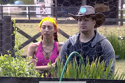 Ruivinha de Marte e Lucas Santos em frente do galinheiro. Ele utiliza o chapéu de fazendeiro