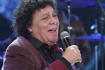 Wanderley Cardoso de blazer magenta e camisa social preta, segurando o microfone com a mão direita durante gravação do Altas Horas, da TV Globo