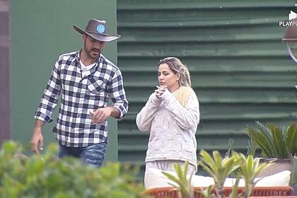 Shay de camisa xadrez ao lado de Deolane na área externa de A Fazenda.