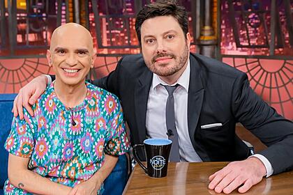 Edson Cordeiro sorrindo, de camisa estampada ao lado de Danilo Gentili durante gravação do The Noite, do SBT