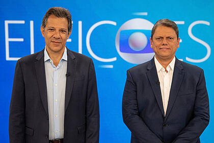 Fernando haddad e tarcísio de freitas posados em frente ao telão, no cenário do debate de 2º turno na tv globo