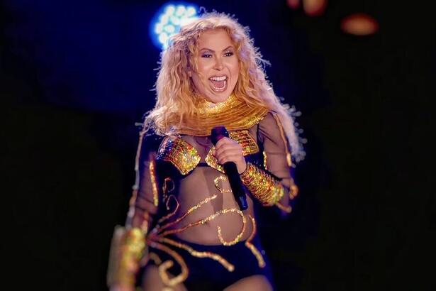 Joelma com a boca aberta segurando o microfone com a mão esquerda durante show