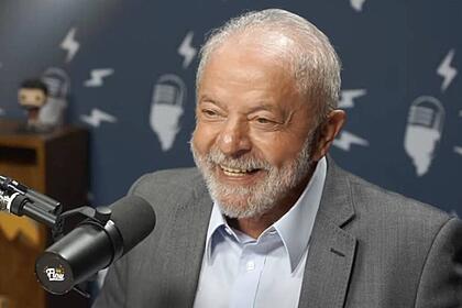 Lula de blazer cinza e camisa social branca sorrindo, sentado
