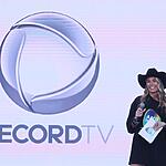 Adriane Galisteu de chapéu de Cowgirl preto, segurando fichas e microfone durante apresentação do Teleton