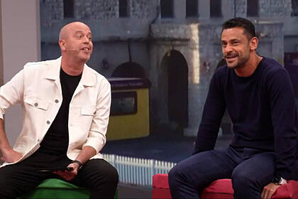 Alex escobar, de roupa presa e caso branco, sentado ao lado de fred, com roupa preta, em trecho do programa central da copa