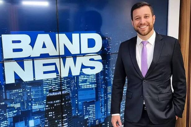 Cassius Zeilmann em foto posada em frente ao telão nos estúdios do BandNews TV