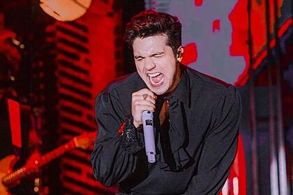 Luan Santana com a boca aberta, segurando um microfone durante performance no Faustão na Band