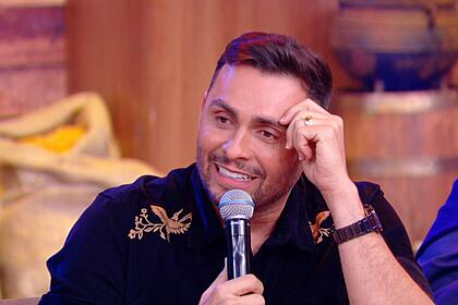 Mano Walter de camisa preta, mão na testa, sorrindo durante gravação do Buteco do Ratinho, do SBT