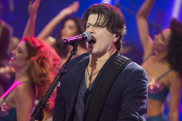 Paulo Ricardo de blazer e camisa preta, cantando durante gravação do Faustão na Band