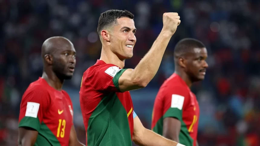 Cristiano Ronaldo, olhando pela lateral, com o braço direito levantando, ao comemorar um gol com a camisa de Portugal