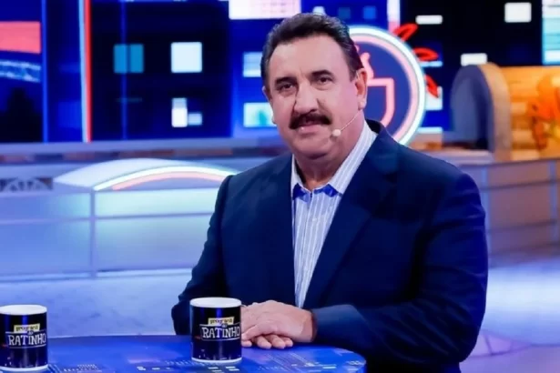 Ratinho de blazer azul marinho, camisa azul clara, com semblante sério, sentado durante gravação do seu programa no SBT