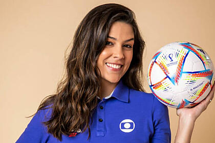 Renata silveira com o uniforme de esporte da globo, sorrindo e segurando uma bola na mão