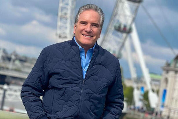 Roberto Justus em foto posada com um casaco azul e mãos no bolso