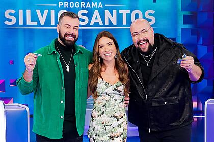 Fernando de jaqueta verde e camisa preta, sorrindo, ao lado esquerdo de Patricia Abravanel; Thiago Abravanel sorrindo ao lado direito de Patrícia durante gravação do Programa Silvio Santos, do SBT