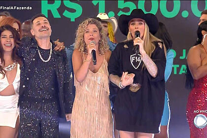 Bárbara borges de mãos dadas com adriane galisteu, com outros participantes ao fundo, em trecho da final de a fazenda 14