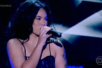 Bell Lins com uma roupa preta, no palco do The Voice Brasil