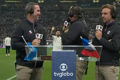 Galvão Bueno, ao lado de Caio Ribeiro e Roger Flores, na beira do gramado, tentando se comunicar com Messi ao fundo, em trecho de transmissão da TV Globo