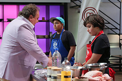 Erick Jacquin de frente para a bancada com dois participantes no MasterChef Júnior