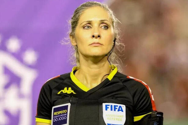 Neuza Back, em foto posada, com o uniforme preto de arbitragem, com os logos da CBF e FIFA estampados