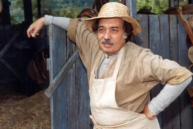 Ator Pedro Paulo Rangel, como o personagem Calixto, em frente uma cerca, na novela O Cravo e a Rosa