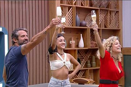 Iran, Bia e Bárbara com a mão levantada segurando uma taça.