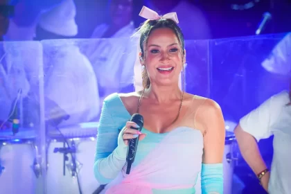 Claudia leitte com look azul e rosa e laço rosa na cabeça durante performance em trio elétrico no carnatal