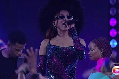 Anitta com óculos escuros com o microfone nas mãos.