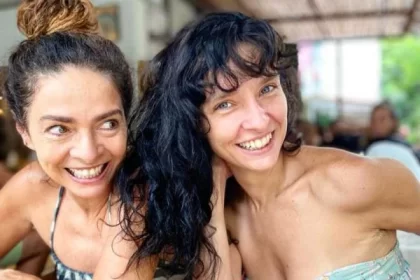 Claudia Ohana de cabelo preso, sorrindo ao lado da filha