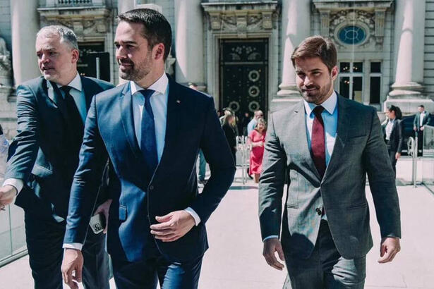 Eduardo Leite chegando a posse ao lado do namorado. Ambos estão de terno e gravata