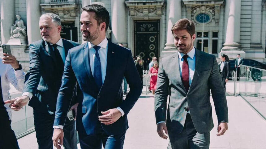 Eduardo Leite chegando a posse ao lado do namorado. Ambos estão de terno e gravata