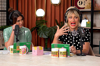 Giovanna Ewbank sentada, de camisa preta com bolinhas brancas abrindo a boca durante entrevista