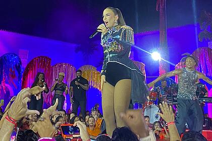 Ivete Sangalo de look preto com brilhantes, cabelo preso, segurando o microfone durante gravação de EP