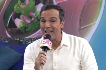 Tadeu Schmidt de camisa branca e calça dentro da Casa de Vidro, apresentando o espaço em chamada