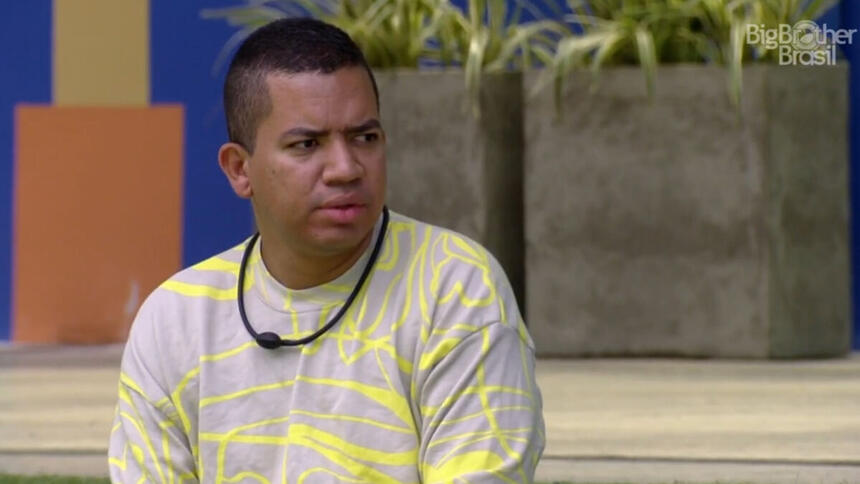 Bruno sentado no gramado da área externa do BBB 23