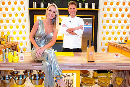 Eliana sentada na bancada de uma das cozinhas do quadro minha mulher que manda, tendo carlos bertolazzi em pé ao fundo, em trecho do programa do sbt