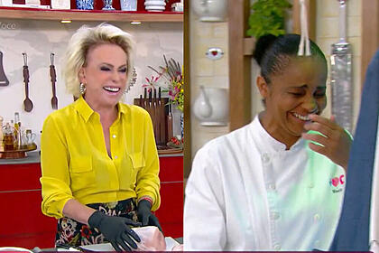 Ana Maria Braga segurando o lombo suíno com a linguiça dentro e sorrindo, ao lado a sua assistente também cai na gargalhada com a piada da apresentadora do Mais Você