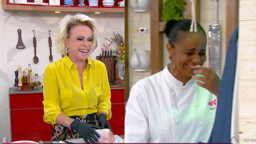 Ana Maria Braga segurando o lombo suíno com a linguiça dentro e sorrindo, ao lado a sua assistente também cai na gargalhada com a piada da apresentadora do Mais Você