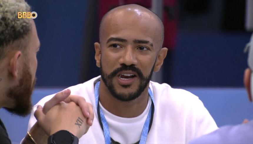 Ricardo sentado olhando para Fred com a boca aberta