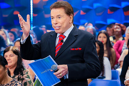 Silvio Santos com uma ficha nas suas mãos, em trecho do Programa Silvio Santos, em frente ao auditório