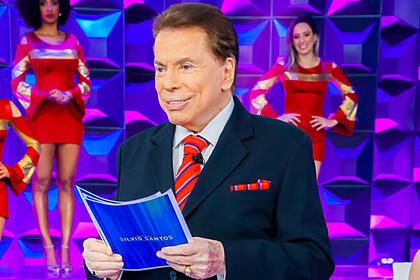 Silvio santos no palco do programa silvio santos, com umas fichas nas mãos
