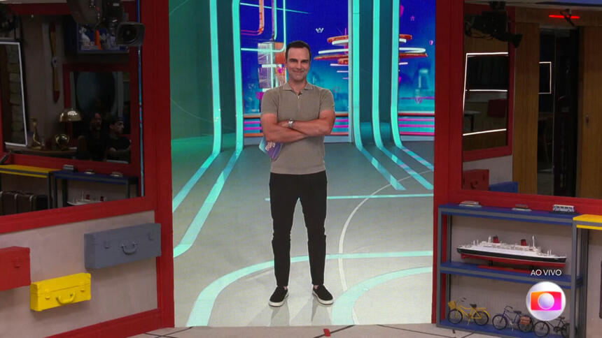 Tadeu Schmidt falando com os brothers do BBB 23, através de um telão na sala da casa