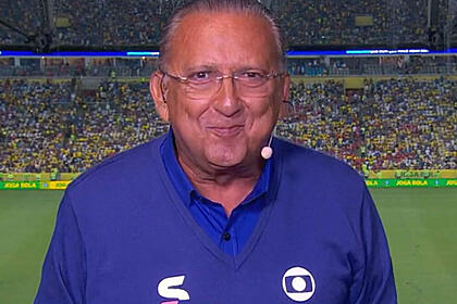 Galvão Bueno nos bastidores de uma transmissão da Globo, com um estádio ao fundo