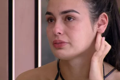 Larissa de cabelo preso, chorando, sentada, em conversa com Marvvila na varanda do BBB 23