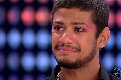 Gabriel Santana chora no cenário do BBB 23, olhando para Tadeu Schmidt