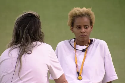 Aline e Amanda de camisa amarela, sentadas, com o microfone no pescoço