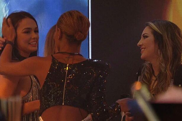 Larissa recebendo abraços de Aline que está de costa na imagem, Amanda, que está de frente e Bruna.