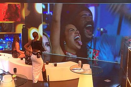 No telão, Ricardo sorrindo ao lado de Paula que está com a língua para fora.