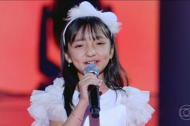 Dani Harumi se apresenta, sorrindo, no palco do The Voice Kids Brasil 8