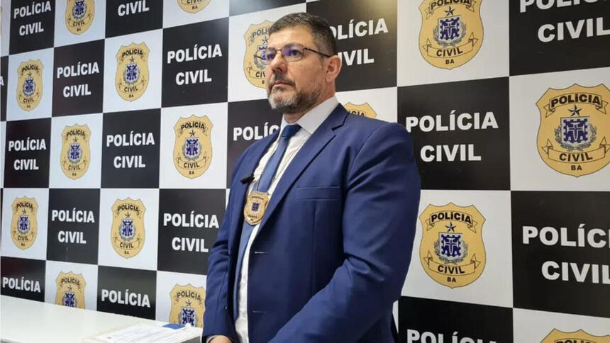 Delegado Charles Leão posando em frente a um banner da Polícia Civil