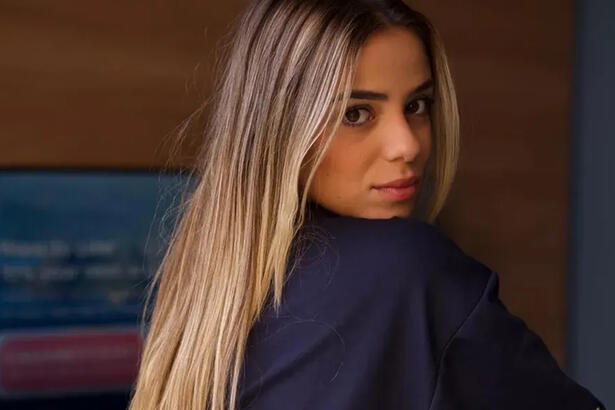 Key Alves de cabelo solto, loiro, de perfil, sentada durante ensaio sensual
